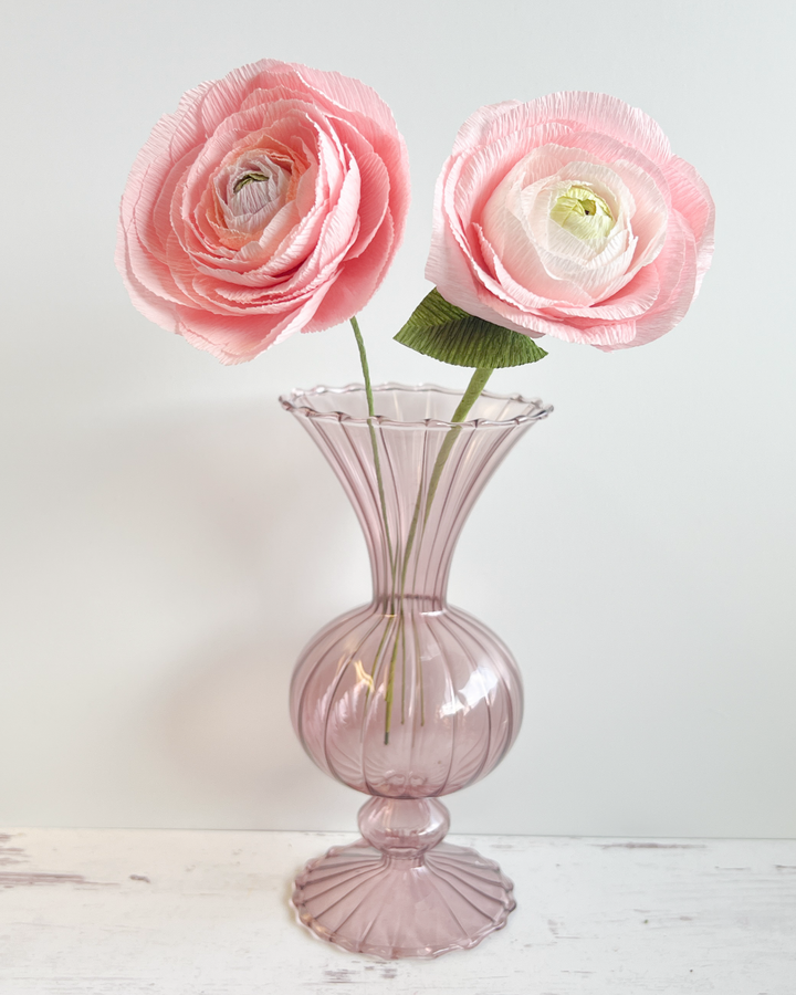 a pink vase with three pink flowers in it