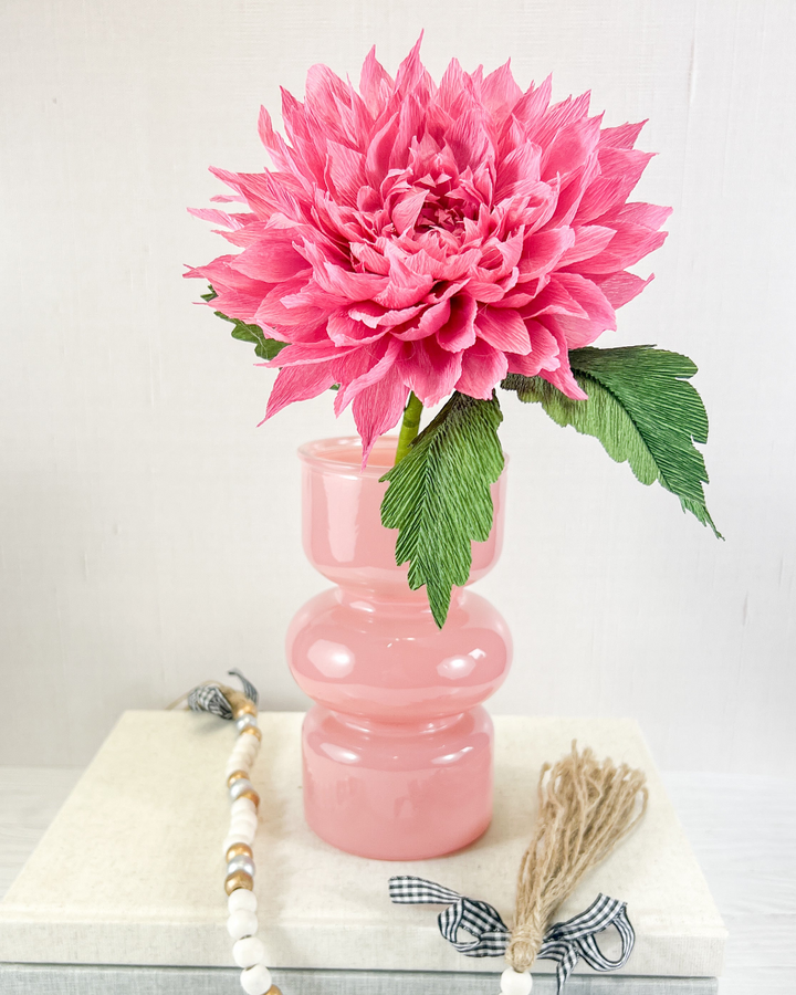 a pink flower in a pink vase on a table