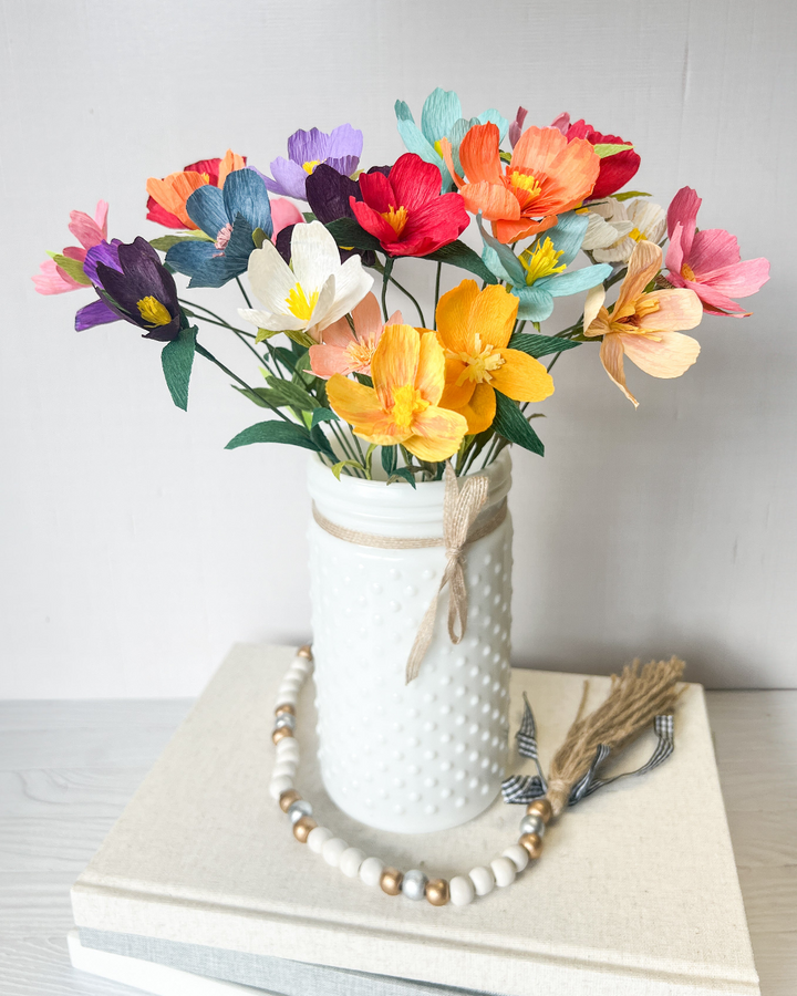 a vase filled with colorful flowers sitting on top of a book