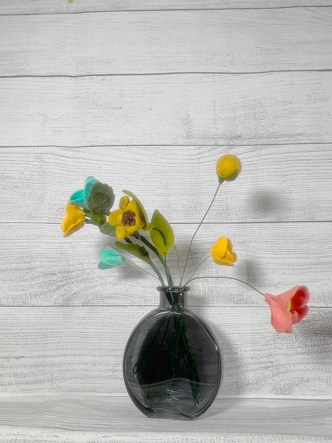 a black vase filled with yellow and red flowers