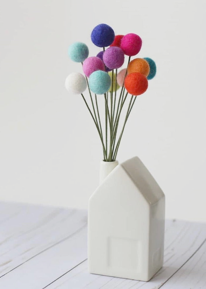 a white vase filled with colorful pom poms