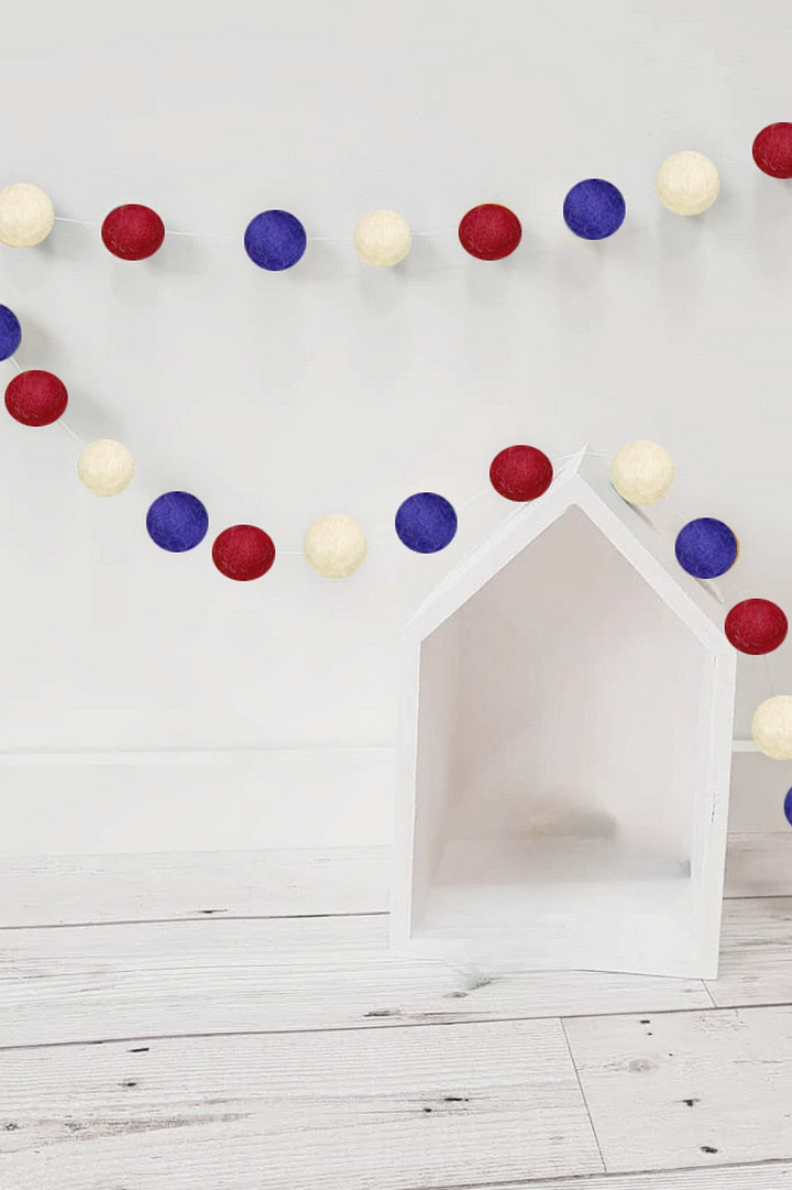 a dog house is decorated with red, white, and blue pom poms